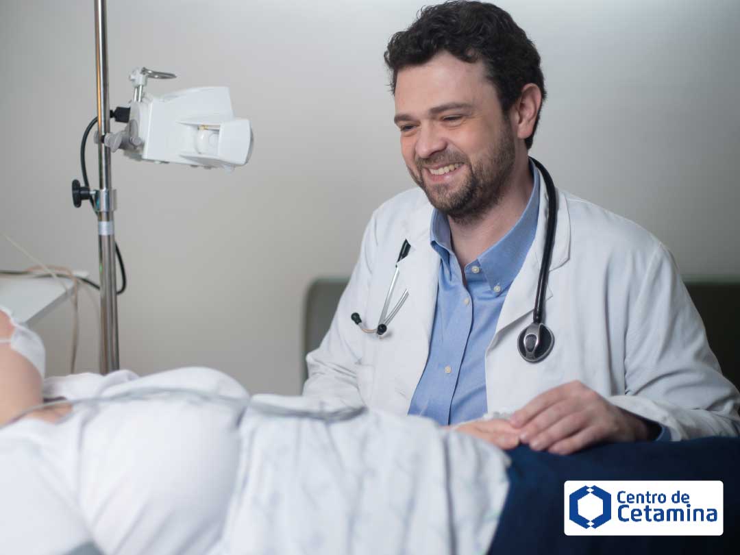 Médico sorridente ao lado de paciente em leito, demonstrando cuidado e acolhimento no tratamento com cetamina.